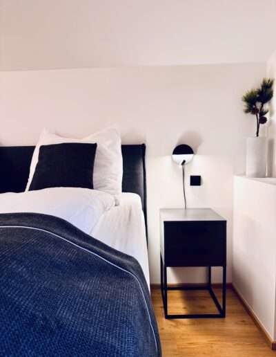 Schlafzimmer mit Boxspringbett, Nachttisch und einer Pflanze